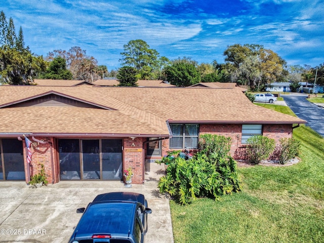 single story home featuring roof with shingles, brick siding, and a front lawn