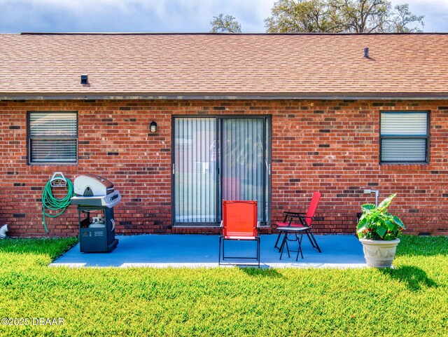 back of house with brick siding and a patio