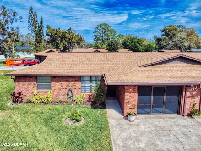 single story home featuring an attached garage, a shingled roof, concrete driveway, and a front yard