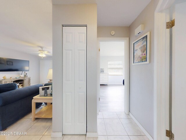 corridor featuring light tile patterned floors and baseboards