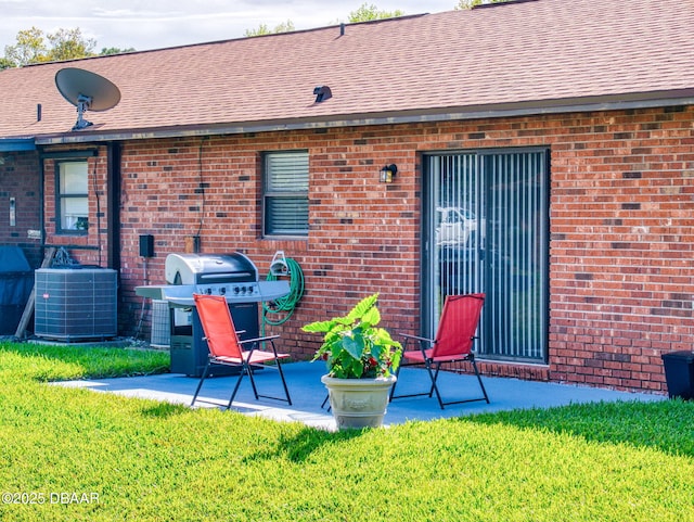 back of property with brick siding, a yard, and a patio