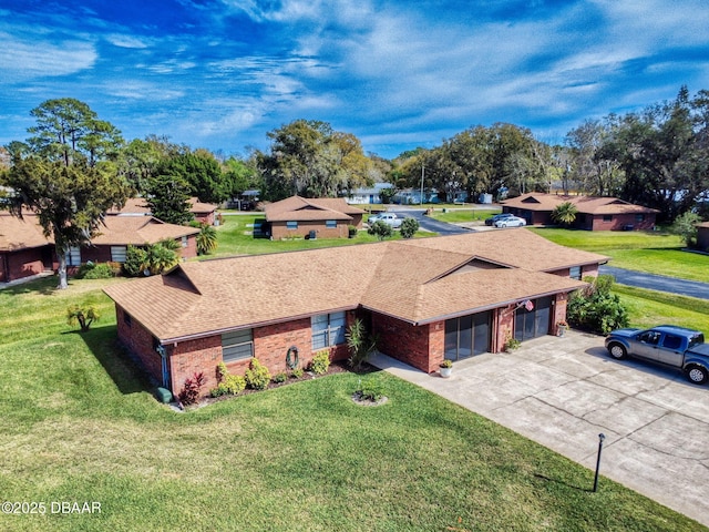 view of front of property featuring driveway, brick siding, roof with shingles, and a front yard