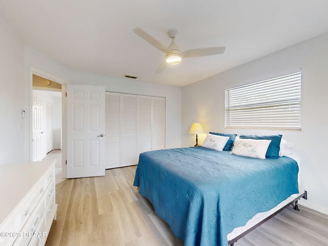 bedroom with light wood-style floors, ceiling fan, visible vents, and a closet