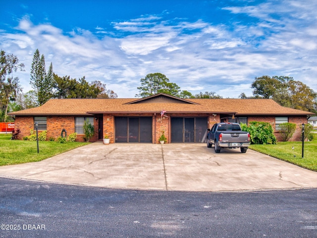 single story home with driveway, brick siding, an attached garage, and a front yard