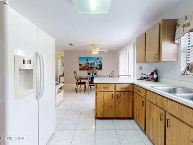 kitchen with ceiling fan, a peninsula, light countertops, white fridge with ice dispenser, and a sink