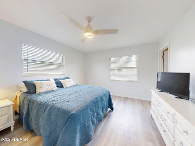 bedroom with a ceiling fan, baseboards, multiple windows, and light wood finished floors