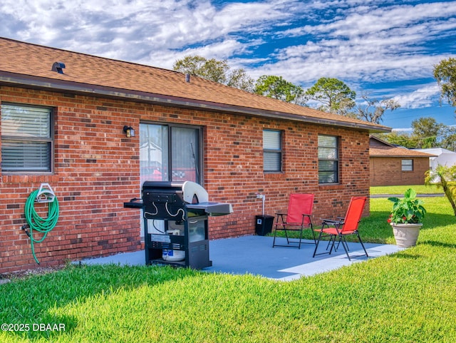 back of house featuring brick siding, a shingled roof, a patio, and a yard