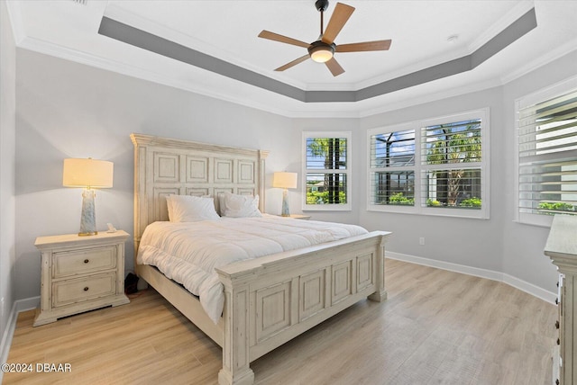 bedroom with ornamental molding, light wood-type flooring, ceiling fan, and a raised ceiling