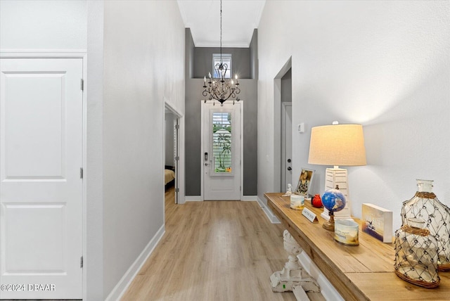 entrance foyer with a notable chandelier, light hardwood / wood-style flooring, and ornamental molding