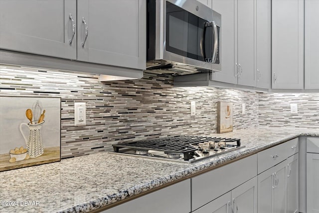 kitchen with light stone countertops, decorative backsplash, and appliances with stainless steel finishes