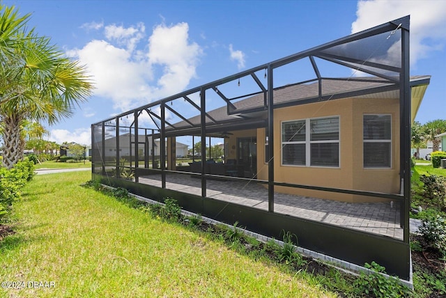 exterior space featuring a lawn, glass enclosure, and a patio