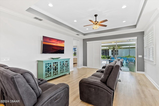 living room featuring a raised ceiling, light hardwood / wood-style floors, and crown molding