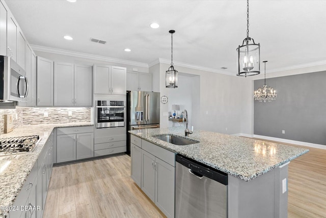 kitchen with stainless steel appliances, light hardwood / wood-style floors, a center island with sink, sink, and pendant lighting