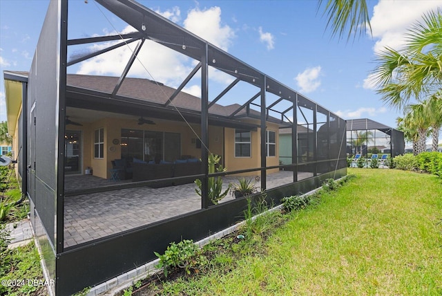 back of property with ceiling fan, a yard, glass enclosure, and a patio area