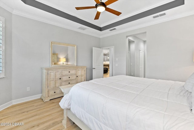 bedroom with ceiling fan, a tray ceiling, light hardwood / wood-style flooring, and ornamental molding