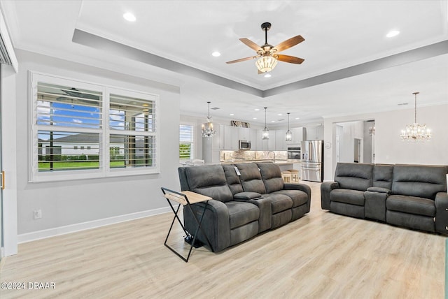 living room with light wood-type flooring, ceiling fan with notable chandelier, and crown molding