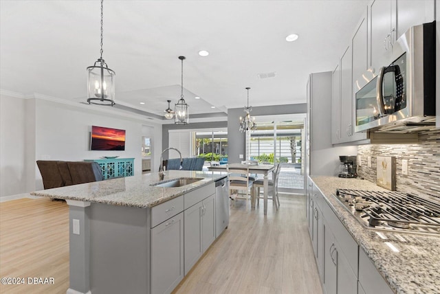 kitchen featuring stainless steel appliances, sink, a kitchen island with sink, gray cabinetry, and light wood-type flooring