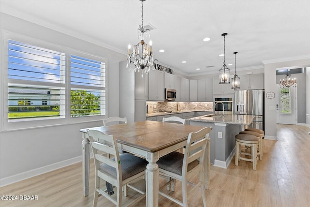 dining room featuring sink, light hardwood / wood-style floors, and crown molding