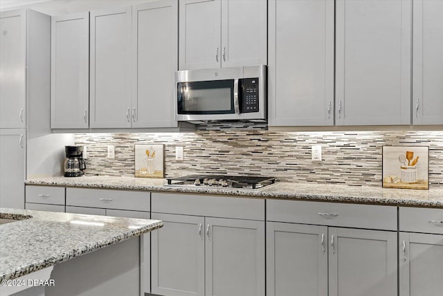 kitchen with stainless steel appliances, light stone countertops, and decorative backsplash