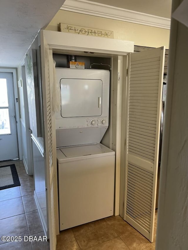 laundry area featuring laundry area, ornamental molding, stacked washer and clothes dryer, and tile patterned floors