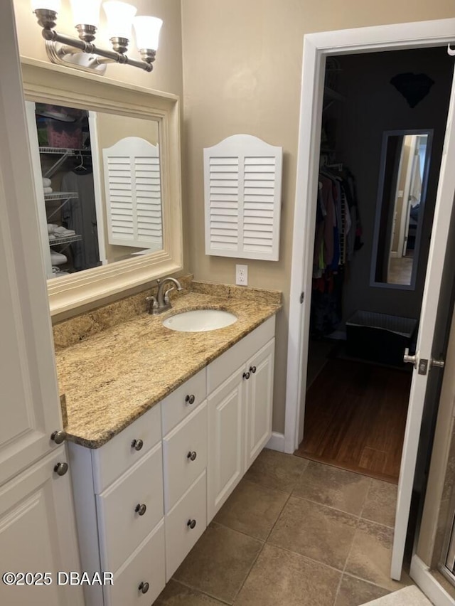 bathroom with tile patterned floors, a walk in closet, and vanity