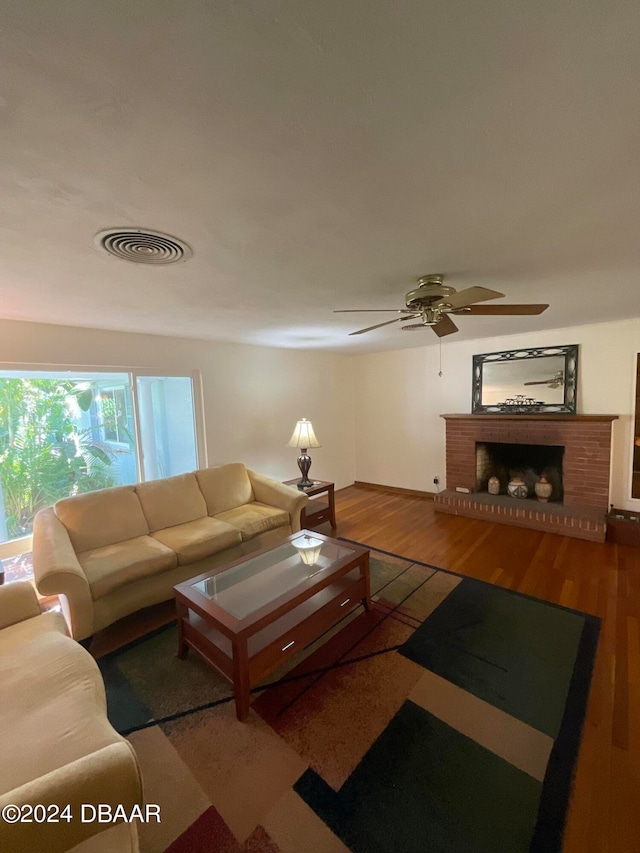 living room with a brick fireplace, hardwood / wood-style floors, and ceiling fan