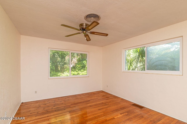 spare room with a textured ceiling, hardwood / wood-style flooring, and ceiling fan