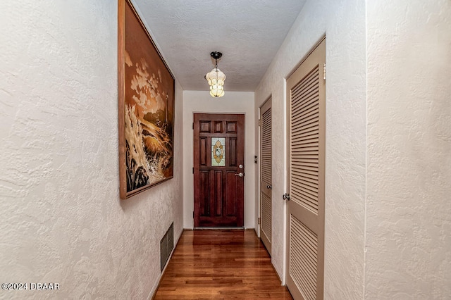 doorway with dark hardwood / wood-style flooring and a textured ceiling