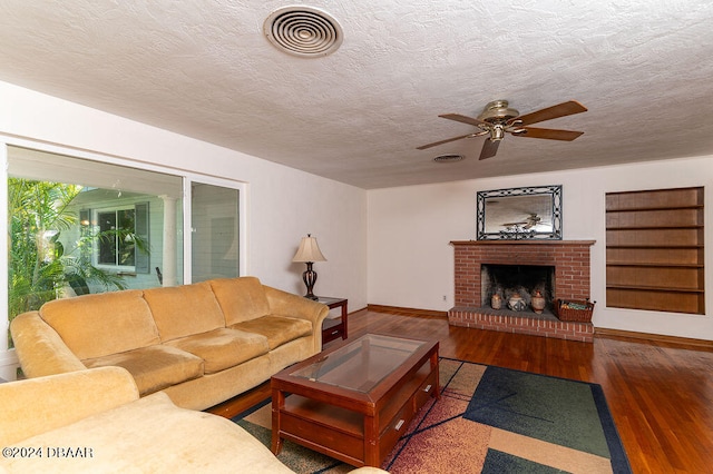 living room featuring a brick fireplace, ceiling fan, a textured ceiling, and dark hardwood / wood-style flooring