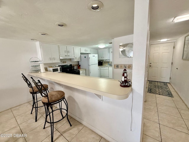 3800 S Atlantic Ave Unit 2010, Daytona Beach Shores, FL 32118 - kitchen with white appliances, under cabinet range hood, light tile patterned floors, a breakfast bar area, and light countertops
