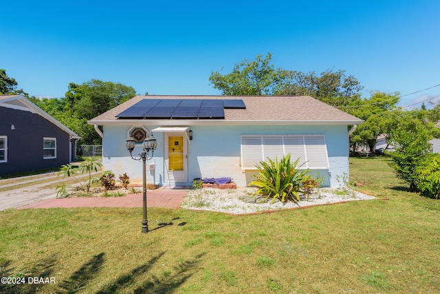 view of front of home with a front lawn and solar panels