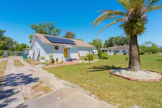 bungalow-style home with a front yard and solar panels