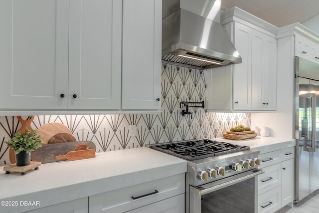 kitchen featuring premium appliances, white cabinets, extractor fan, and tasteful backsplash