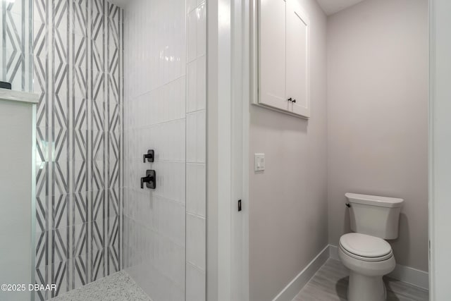 bathroom featuring toilet and a tile shower