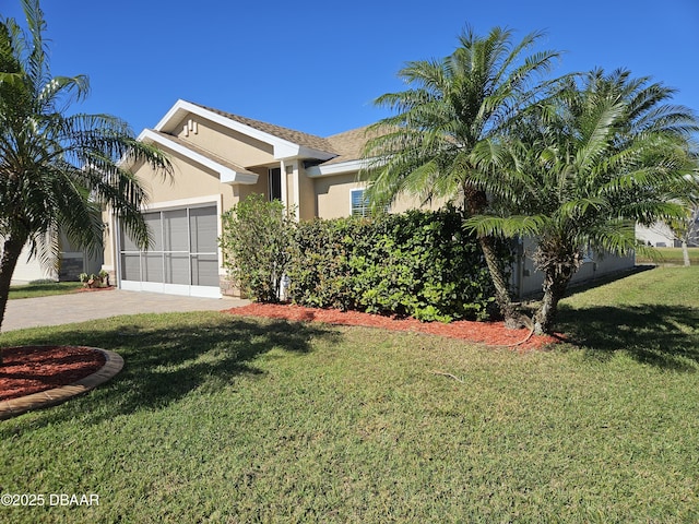 view of front facade with a front lawn, decorative driveway, an attached garage, and stucco siding