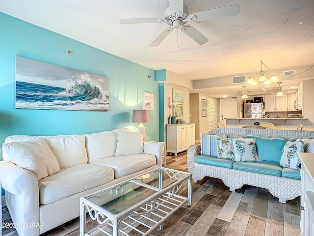 living room with ceiling fan with notable chandelier