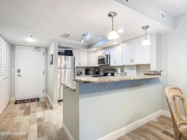 kitchen with stainless steel appliances, white cabinets, decorative light fixtures, and kitchen peninsula