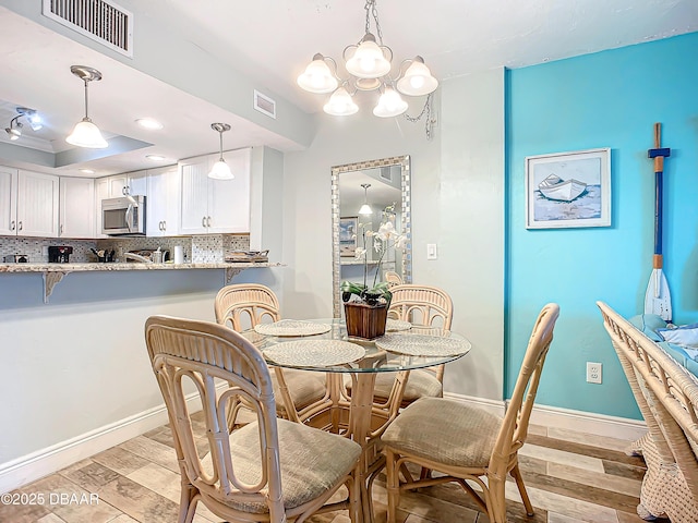 dining area with an inviting chandelier, light wood-type flooring, and a tray ceiling