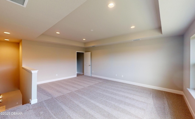 empty room featuring a tray ceiling and light colored carpet