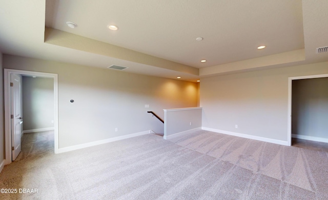 unfurnished room with light colored carpet and a raised ceiling