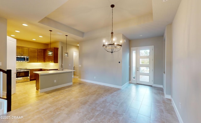 kitchen with sink, appliances with stainless steel finishes, a raised ceiling, pendant lighting, and backsplash