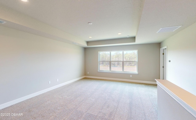 carpeted spare room with a raised ceiling