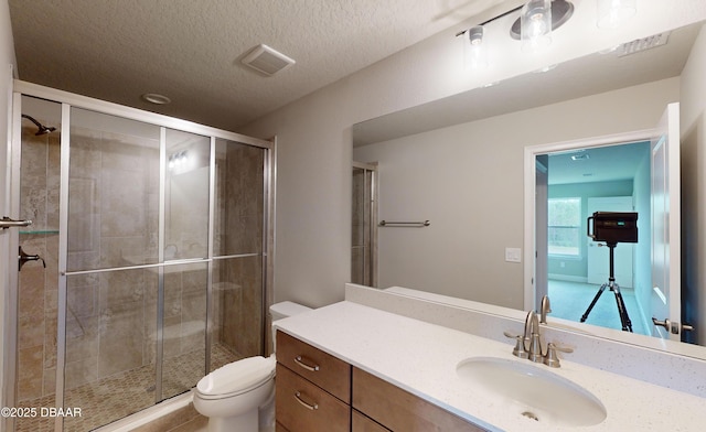 bathroom featuring walk in shower, vanity, a textured ceiling, and toilet