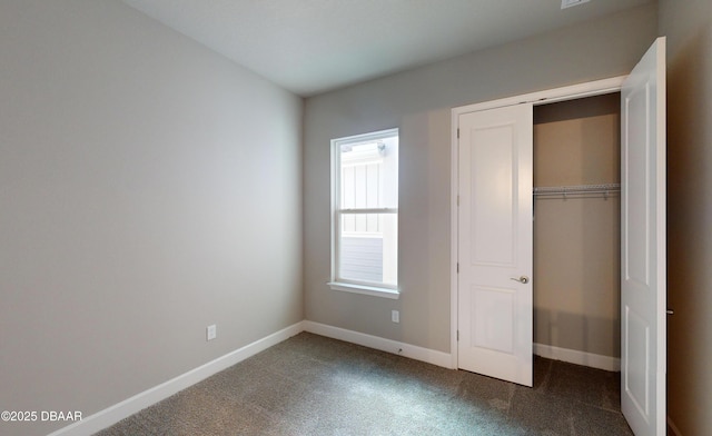 unfurnished bedroom with dark carpet and a closet