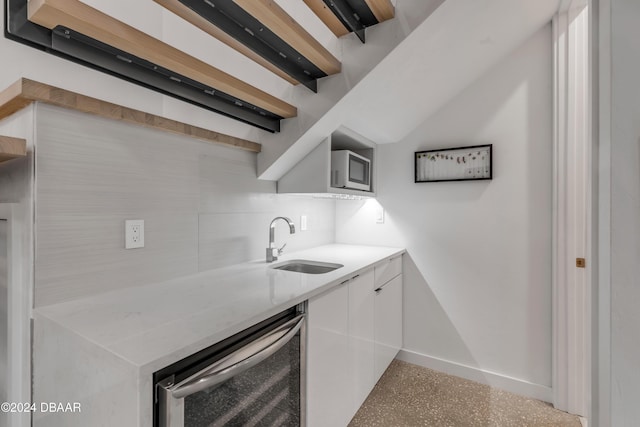 kitchen with white cabinetry, beverage cooler, and sink