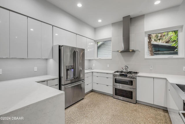 kitchen featuring white cabinets, wall chimney exhaust hood, and high end appliances