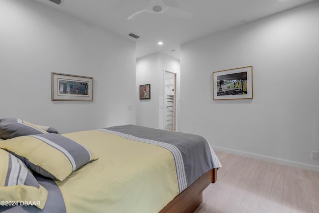 bedroom with a walk in closet, light wood-type flooring, a closet, and ceiling fan