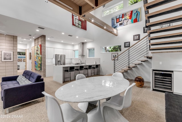 dining area featuring beamed ceiling, a towering ceiling, and sink