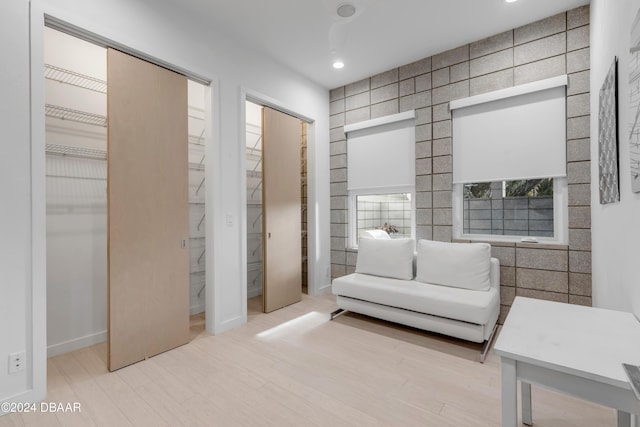 living area with light wood-type flooring and tile walls