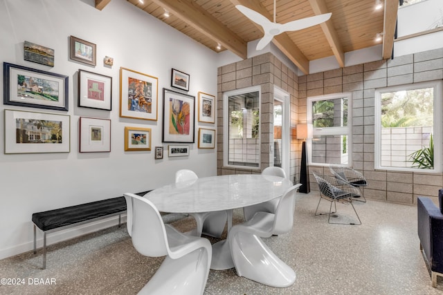 dining area featuring beam ceiling, ceiling fan, wooden ceiling, and tile walls